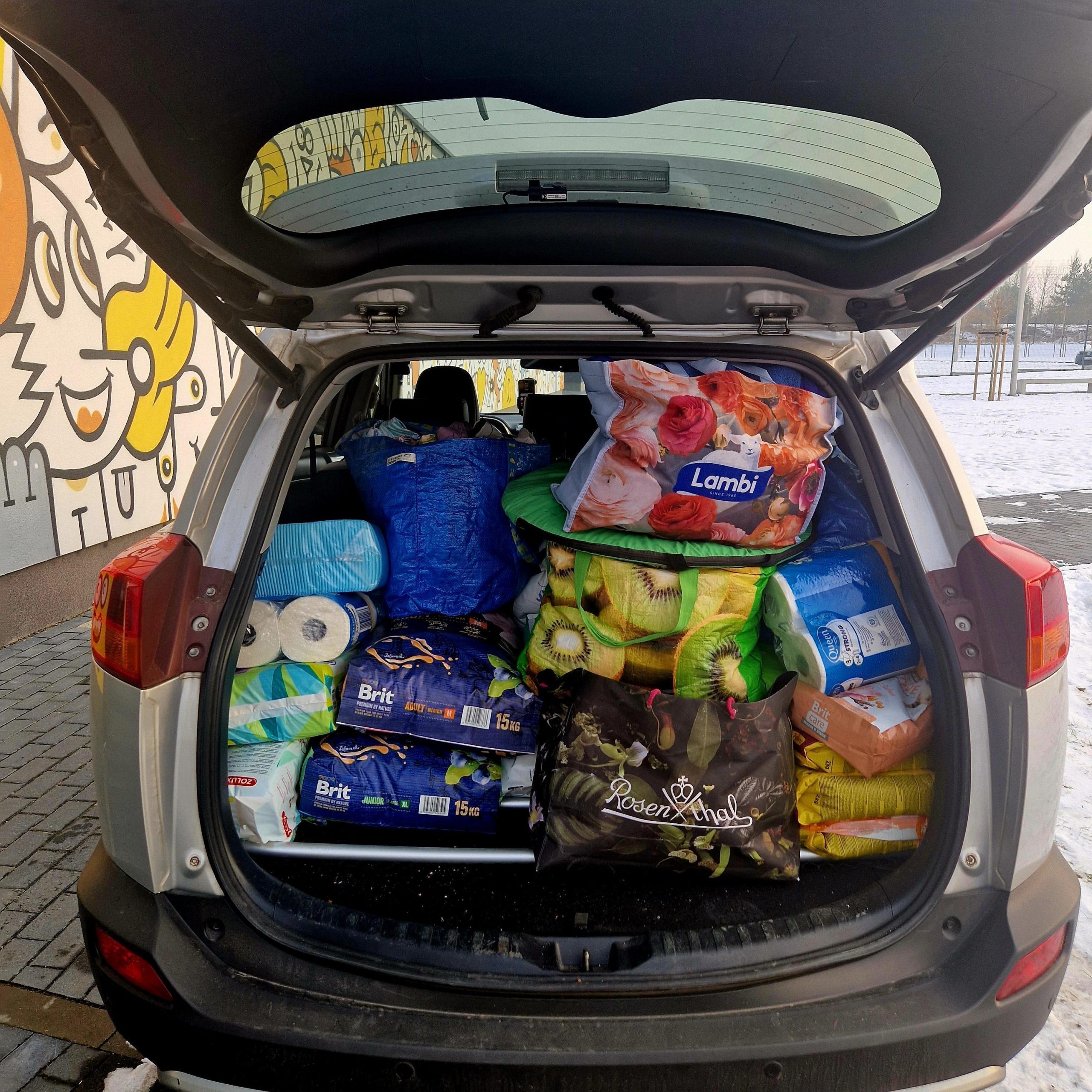 Widok bagażnika uta typu SUV z przywiezionymi do schroniska karmami dla zwierząt, kocami, ręcznikami.