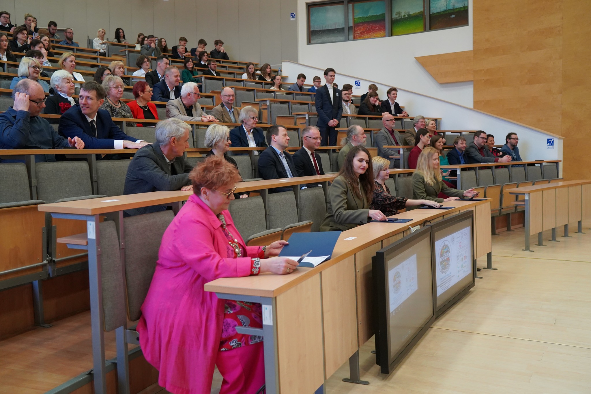 Widok na salę, na której odbywa się Olimpiada Geograficzna, na sali wykładowej siedzą uczestnicy i jury Olimpiady.