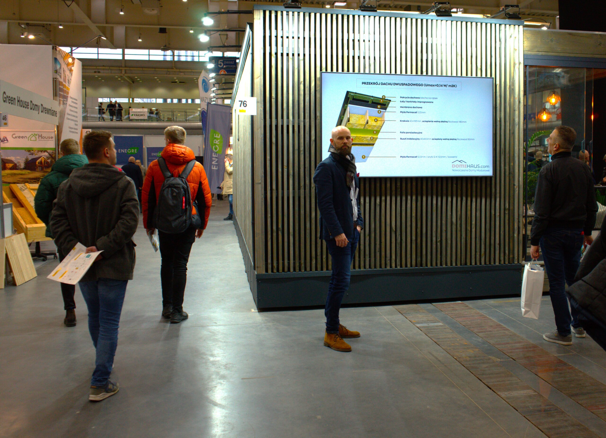 Widok hali targowej, jedna osoba stoi na tle ściany i ekranu