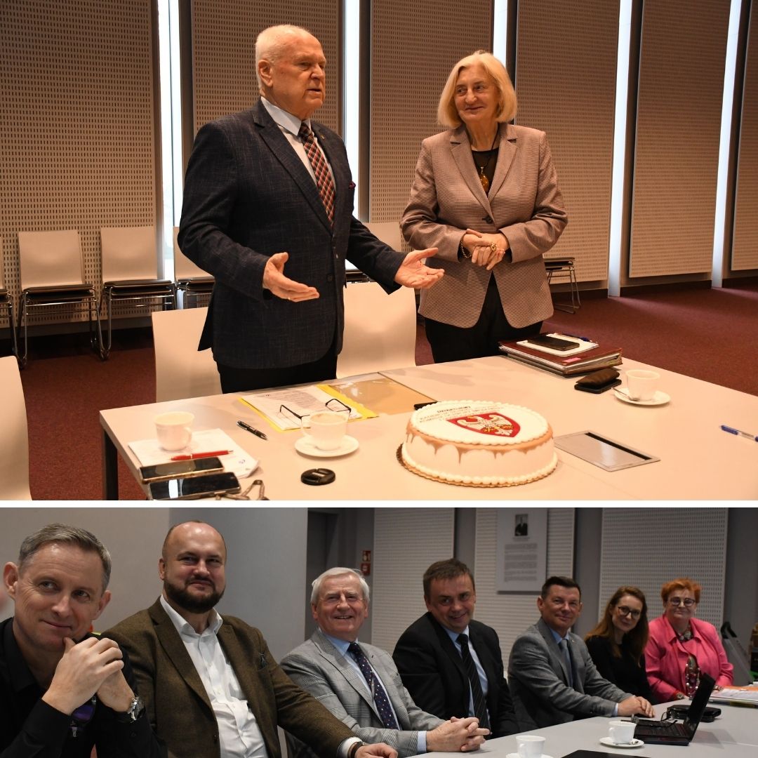 2osoby stoją za stołem na którym stoi tort, a 6 osób siedzi za stołem.