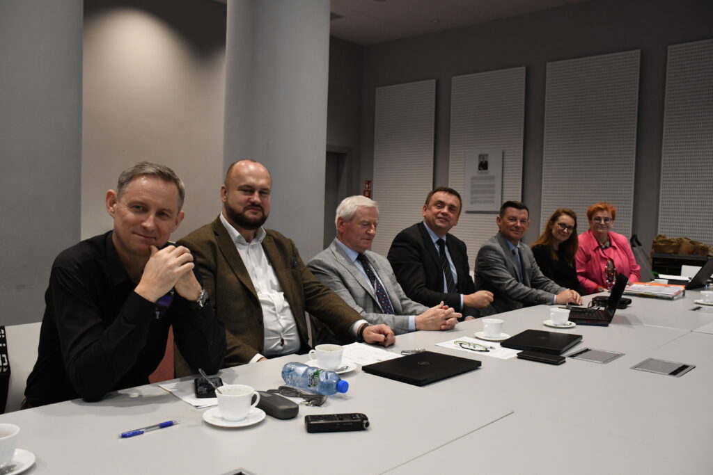 6 osób siedzi za stołem i rozmawia