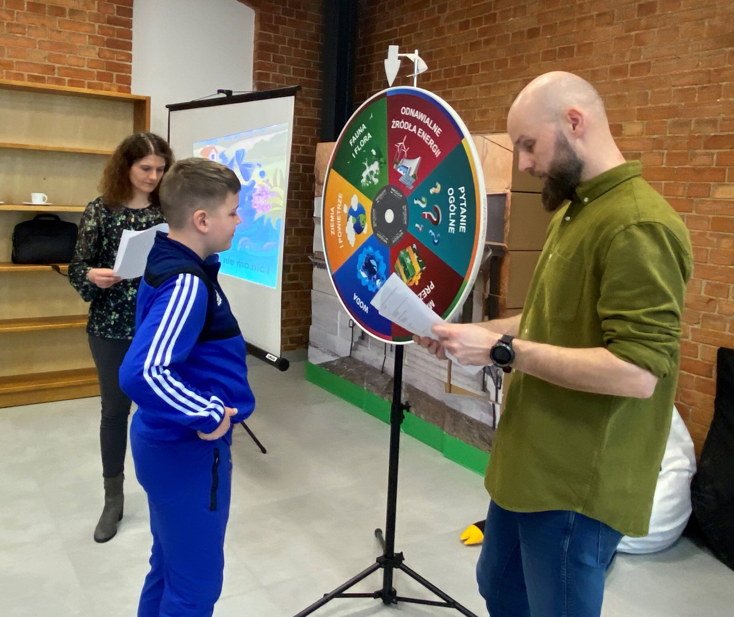 Podczas warsztataów z okazji Dnia Wody w Szkole Podstawowej w Drawsku uczeń stoi przy kole fortuny i odpowiada na pytanie.