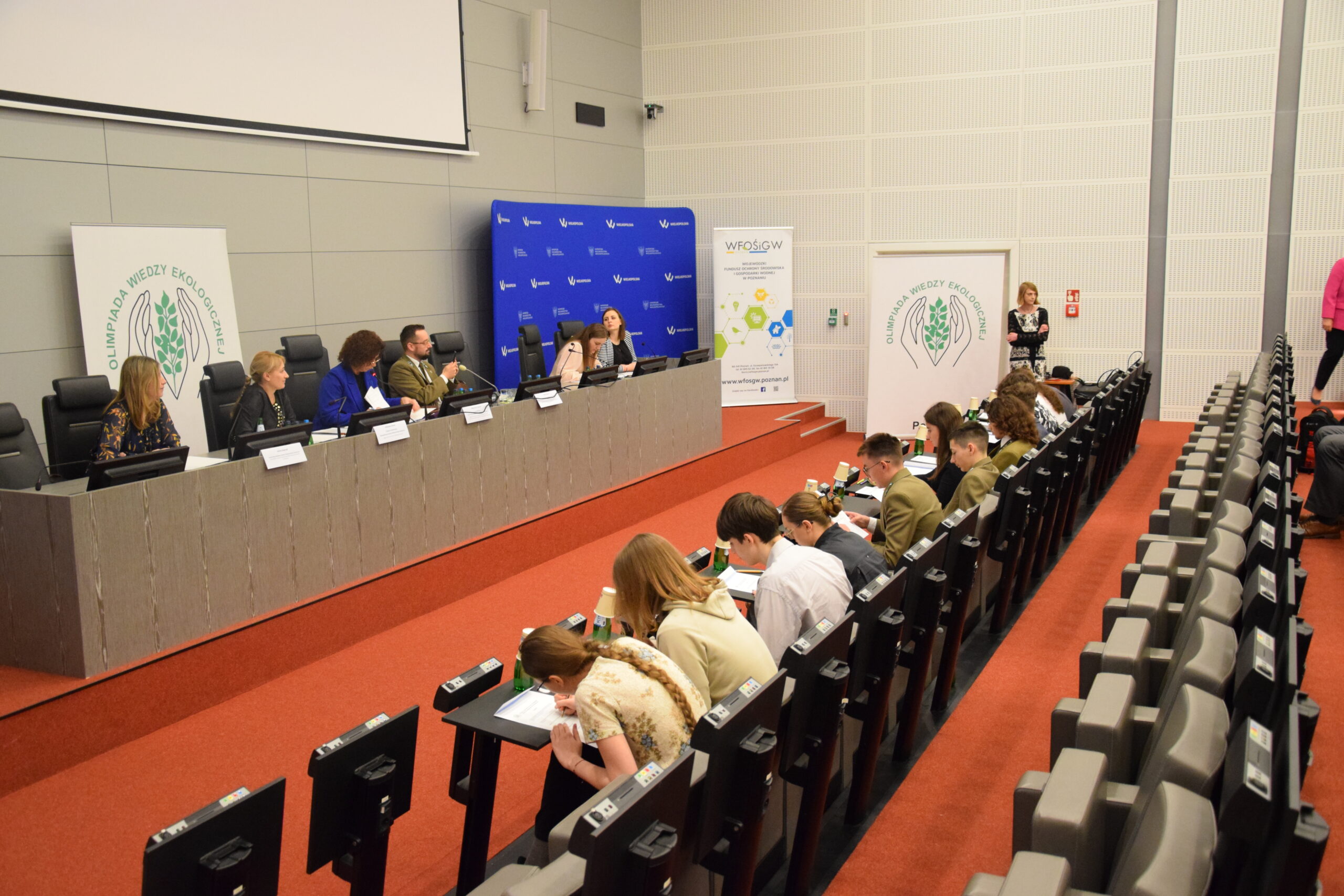 Część ustna olimpiady - komisja siedzi za stołem, a naprzeciwko w pierwszym rzędzie siedzą uczzniowie.