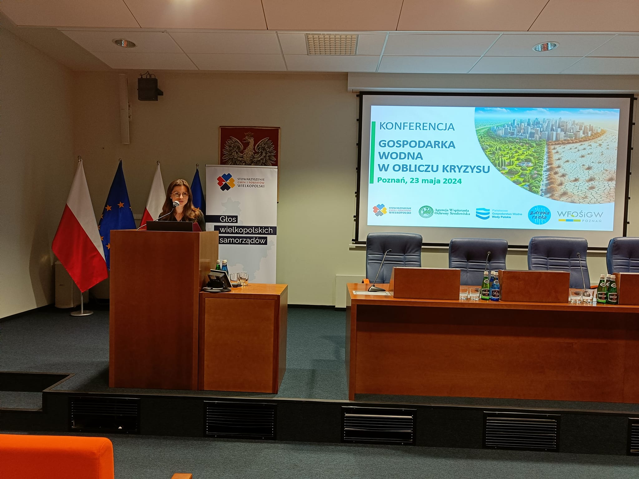 Wojewoda Wielkopolska, Agata Sobczak, stoi na scenie, na tle wyświetlanej prezentacji i przedstawia prelekcję.