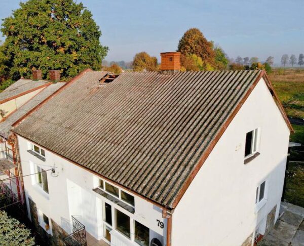 Zdjęcie przedstawia stary dom pokryty azbestem.