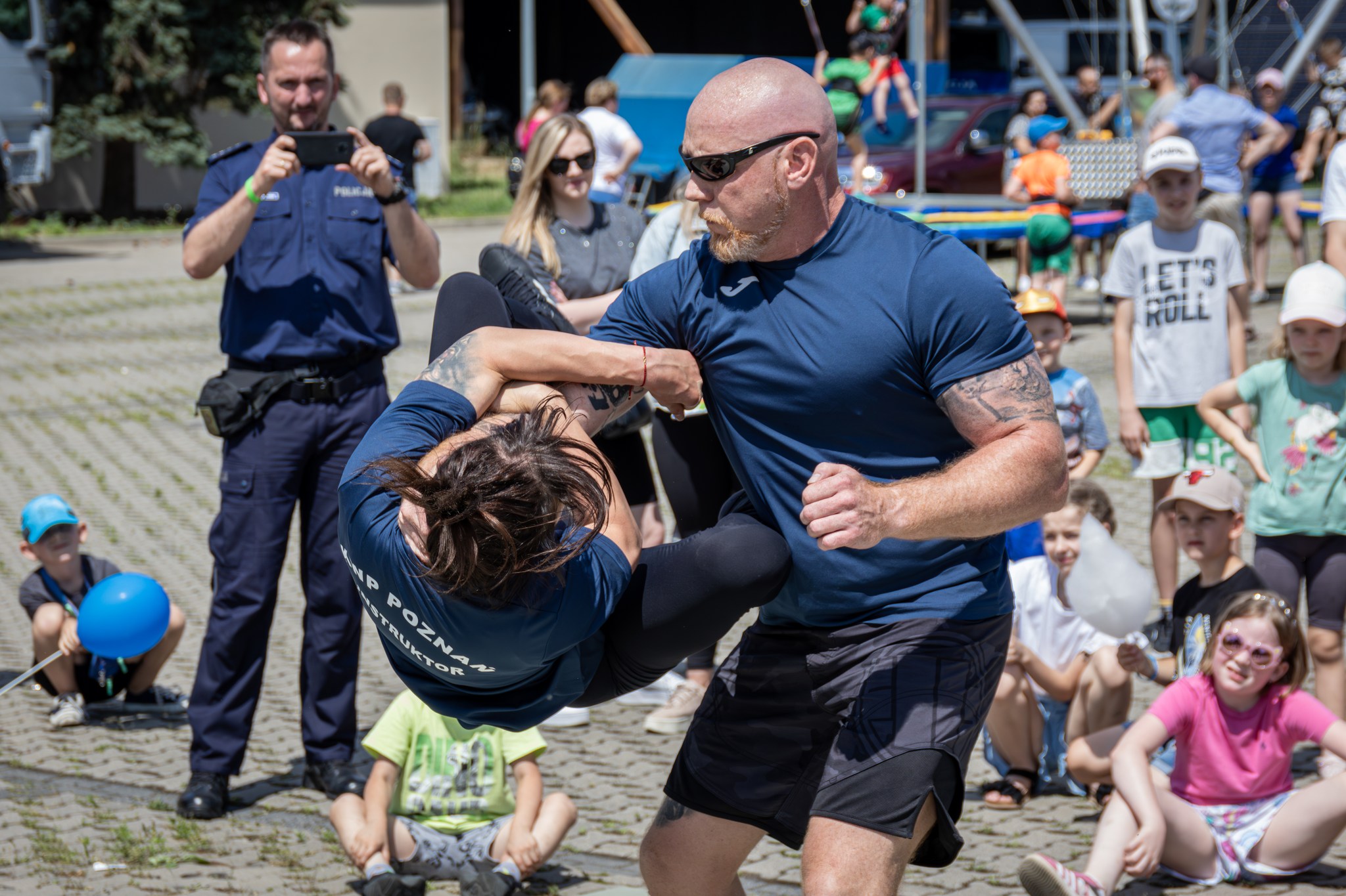 Na zdjęciu pokaz walki i samoobrony w wykonaniu policji. Na placu, na którym odbywał się piknik, dwóch policjantów prezentuje walkę.