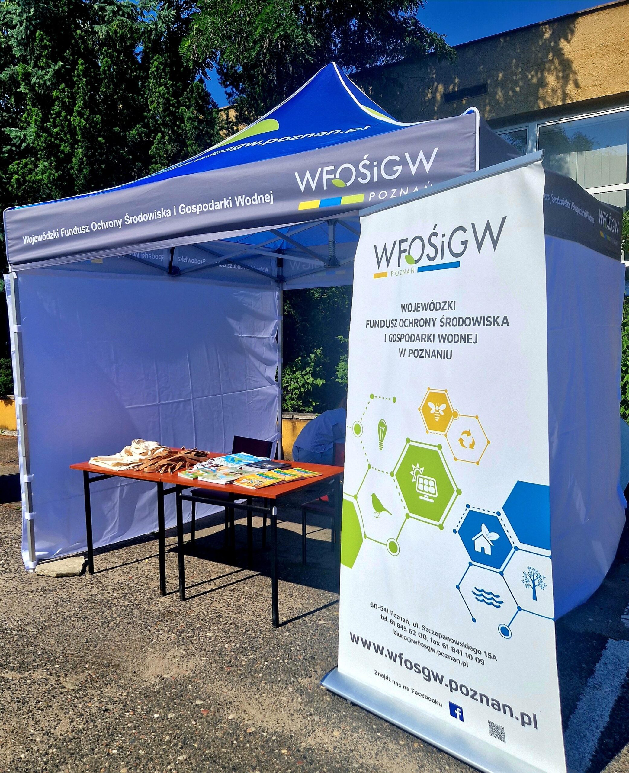 Stoisko WFOŚiGW w Poznaniu - namiot a pod namiotem stół, krzesła i rollup reklamowy.