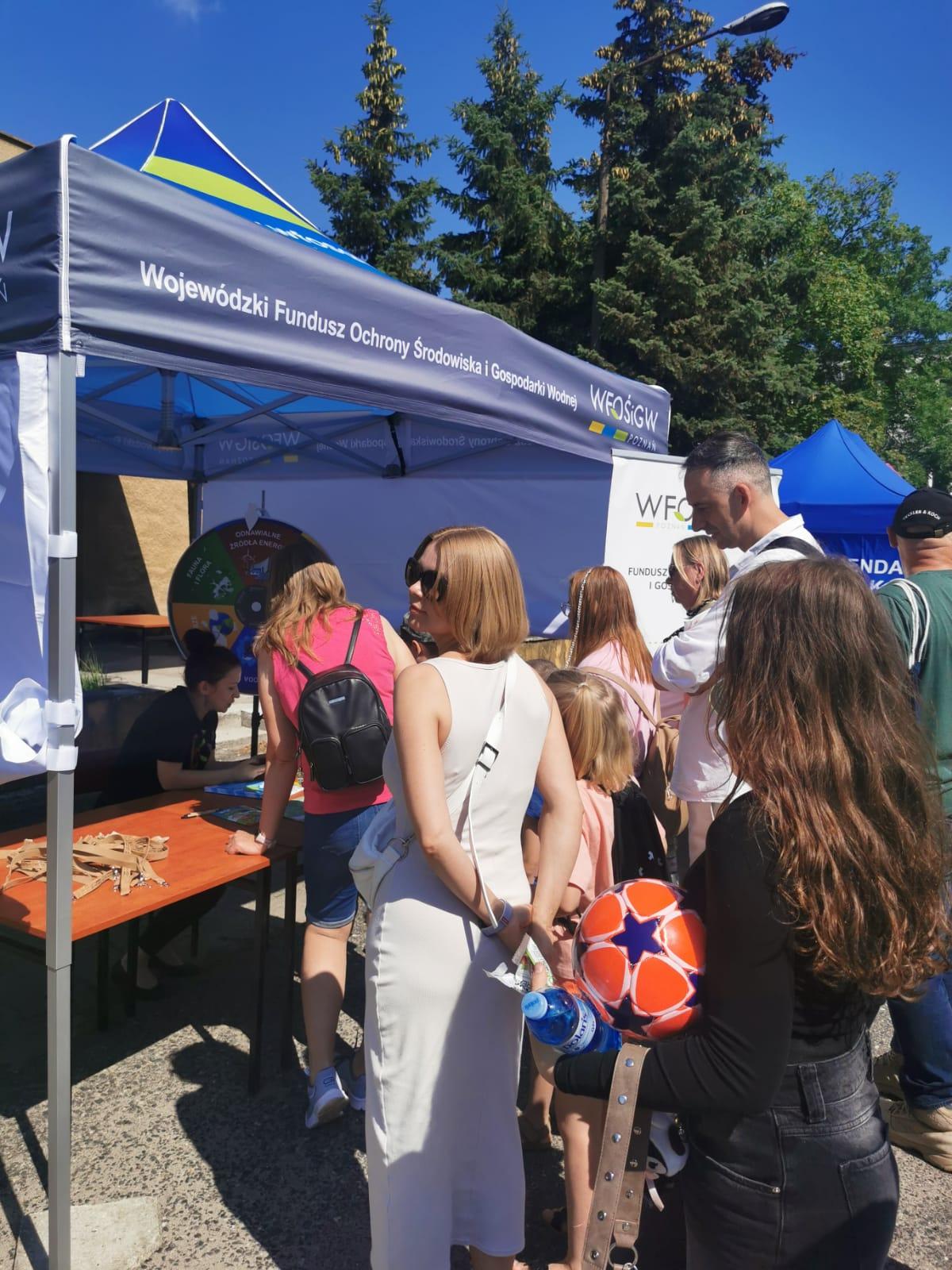 Stoisko WFOŚiGW w Poznaniu, przed namiotem stoją dzieci i dorośli.