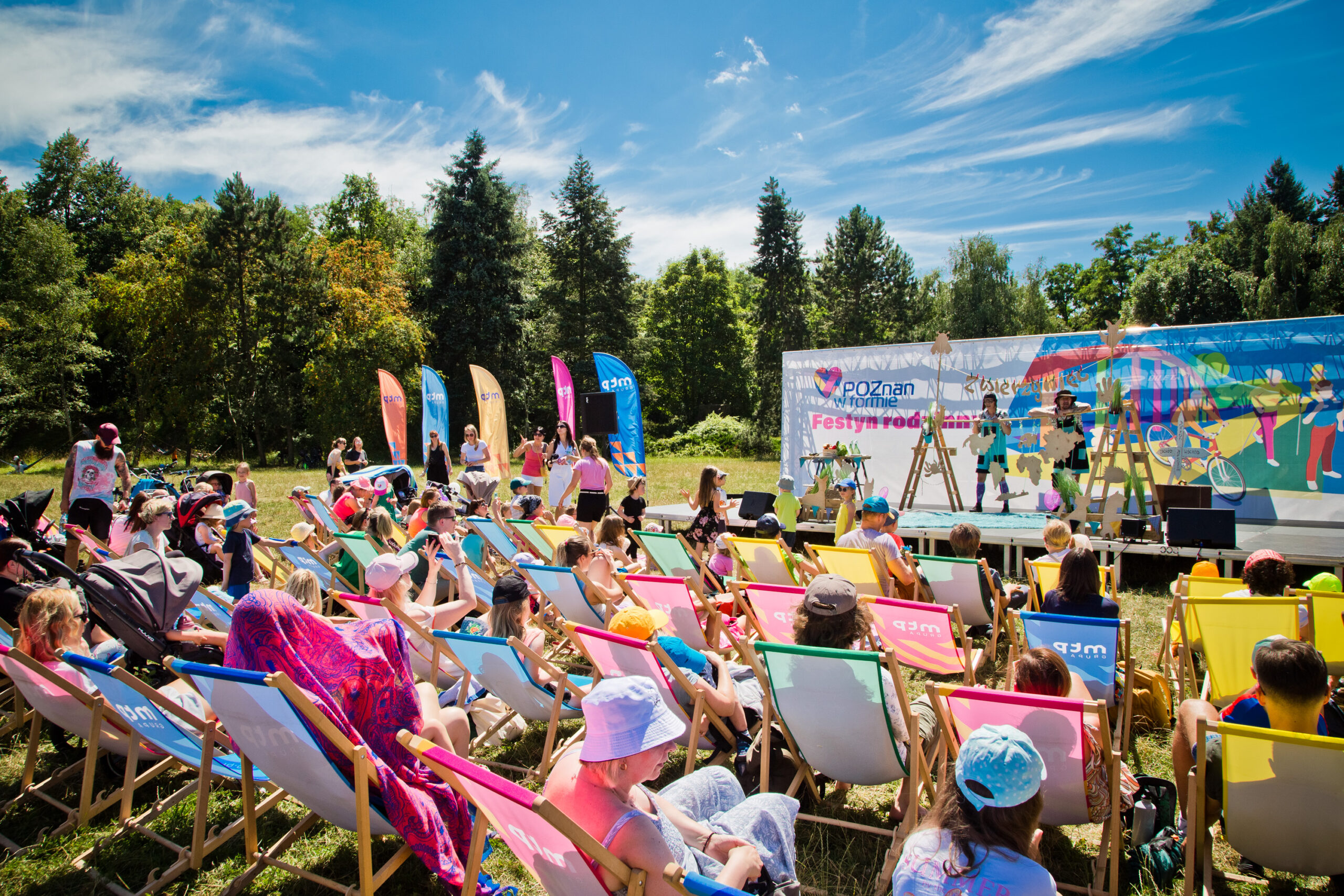 Na zdjęciu widać scenę, na której odbywa się przedstawienie oraz ludzi zgromadzonych na leżakach przed sceną.