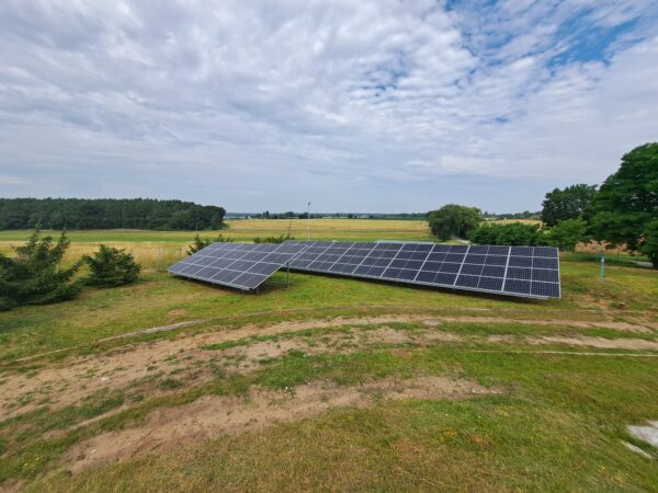 Na zdjęciu, na pustej przestrzeni stoją panele fotowoltaiczne.