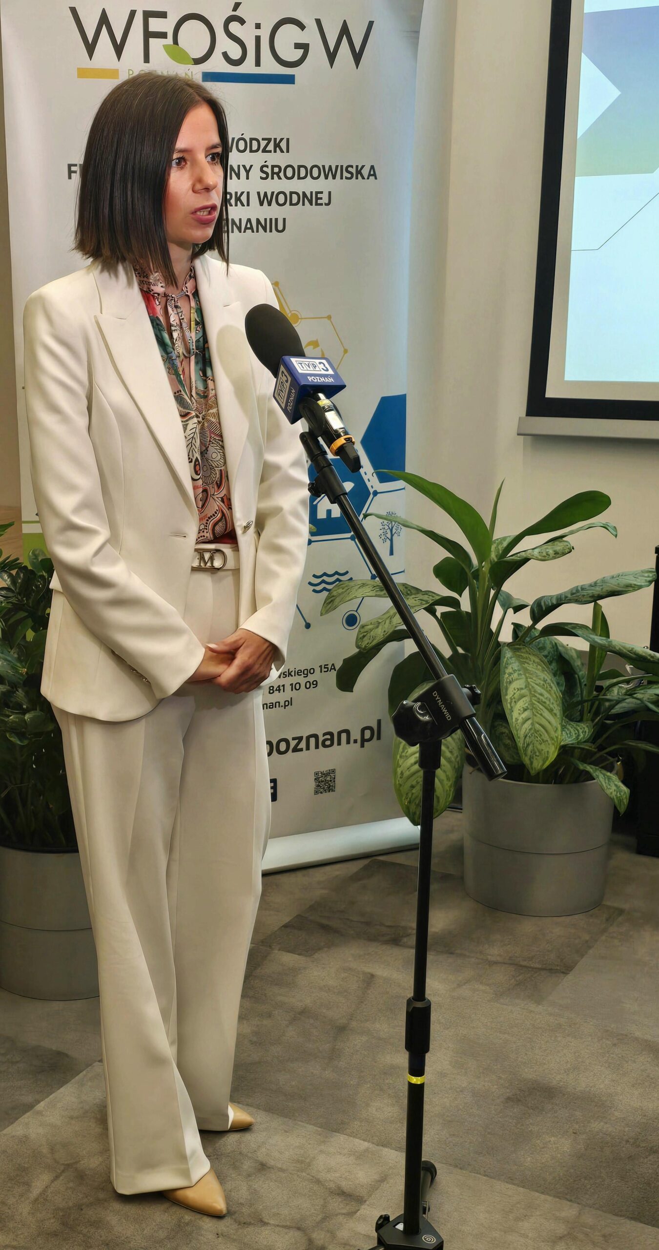 Jedna osoba stoi i udziela wypowiedzi dziennikarzom do kamery.