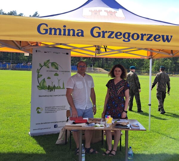 Zdjęcie przedstawia Doradców Klimatyczno-Energetycznych pod namiotem Gminy Grzegorzew, przed nimi stoi stół z materiałami informacyjno-promocyjnymi.