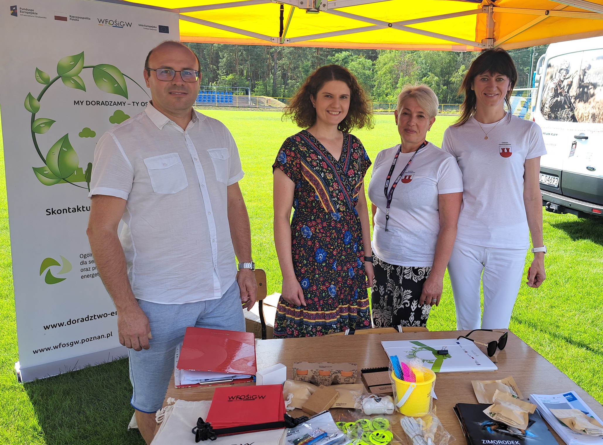 Na zdjęciu, ppdczas wydarzenia, pod namiotem dozdjęcia pozują 4 osoby - dwoje doradców klimatyczno-energetycznych z WFOŚiGW w Poznaniu i dwie Panie z Urzędu Gminy Grzegorzew.