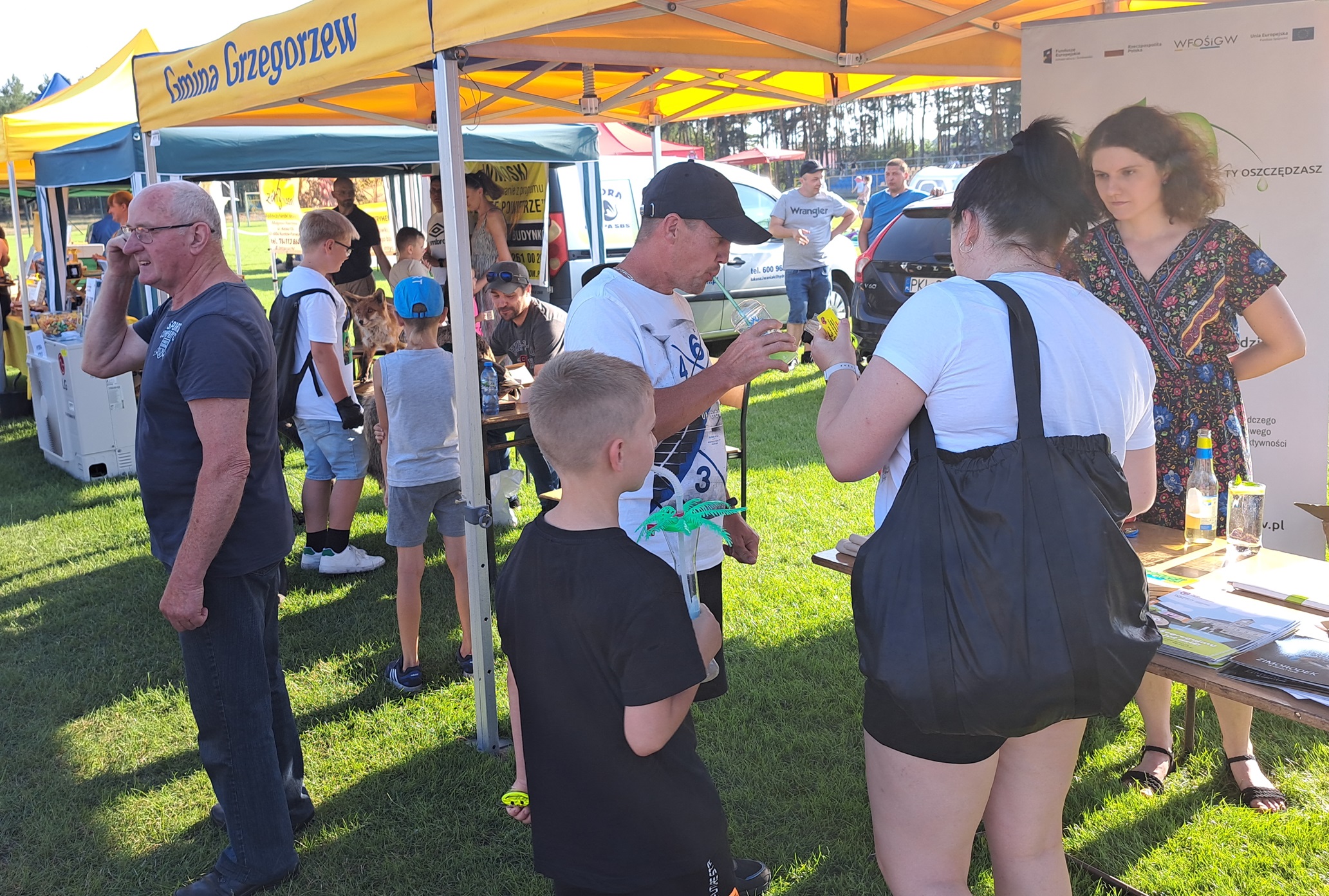 Na zdjęciu widać ludzi stojących przy stoisku WFOŚiGW w Poznaniu, doradca klimatyczno-energetyczny udziela im informacji.