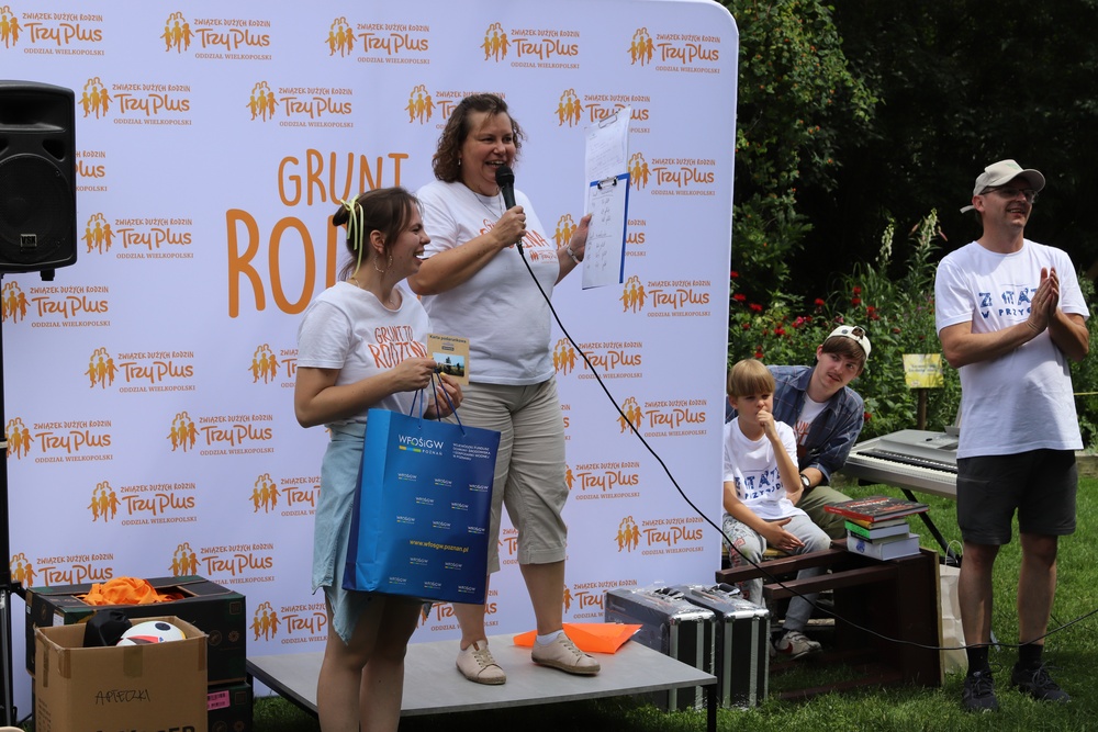 Na zdjęciu mała scena i na tle bannera reklamowego następuje wręczenie nagród.