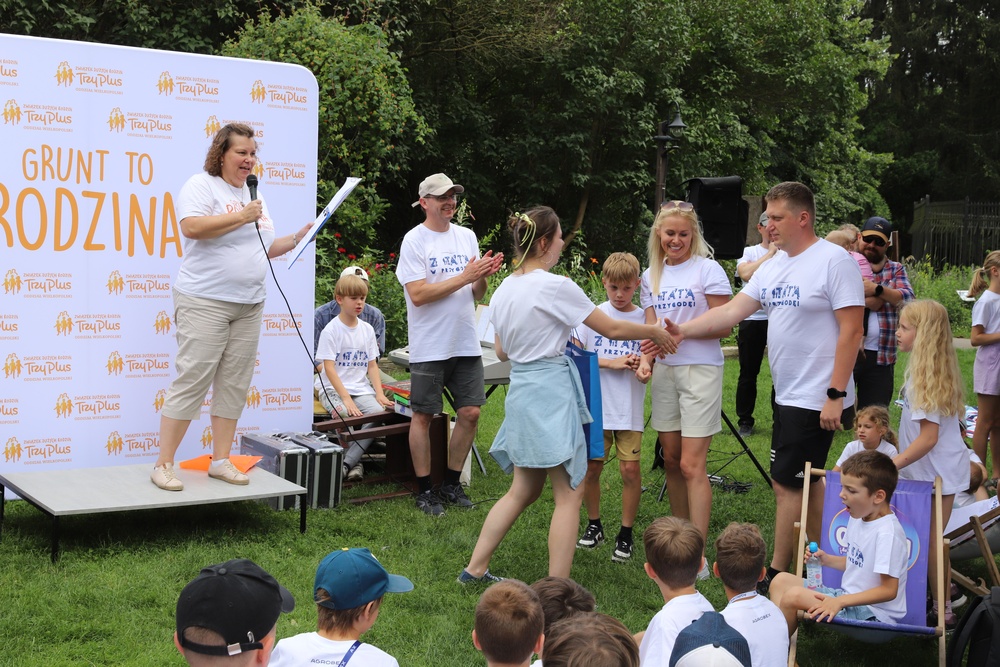 Na zdjęciu mała scena i na tle bannera reklamowego następuje wręczenie nagród.