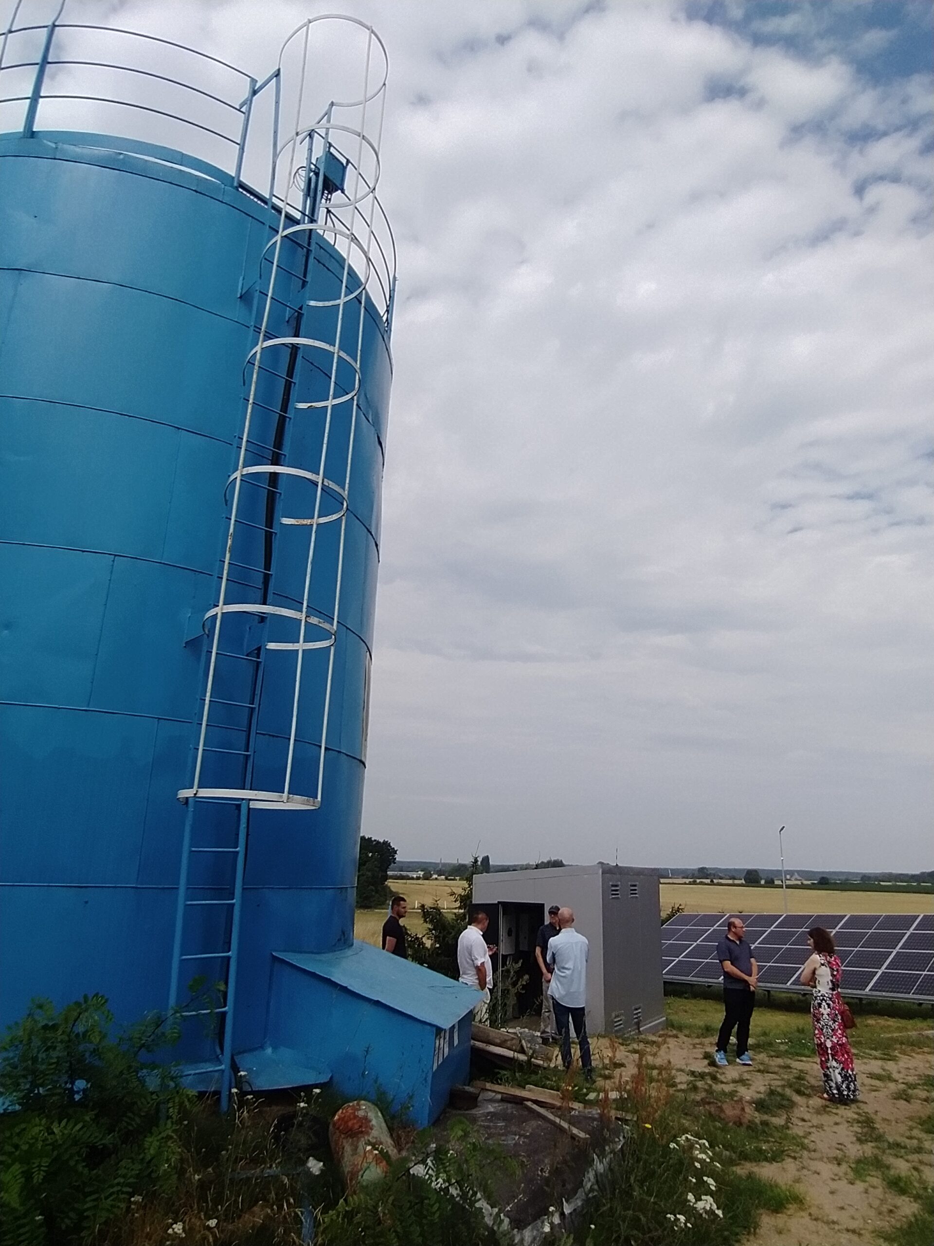 Doradcy energetyczni podczas zwiedzania spółdzielni energetycznej, na zdjęciu duże urządzenie stojące na zewnątrz.