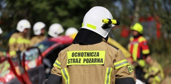 Na zdjęciu stoi tyłem strażak z Ochotniczej Straży Pożarnej w mundurze bojowym.