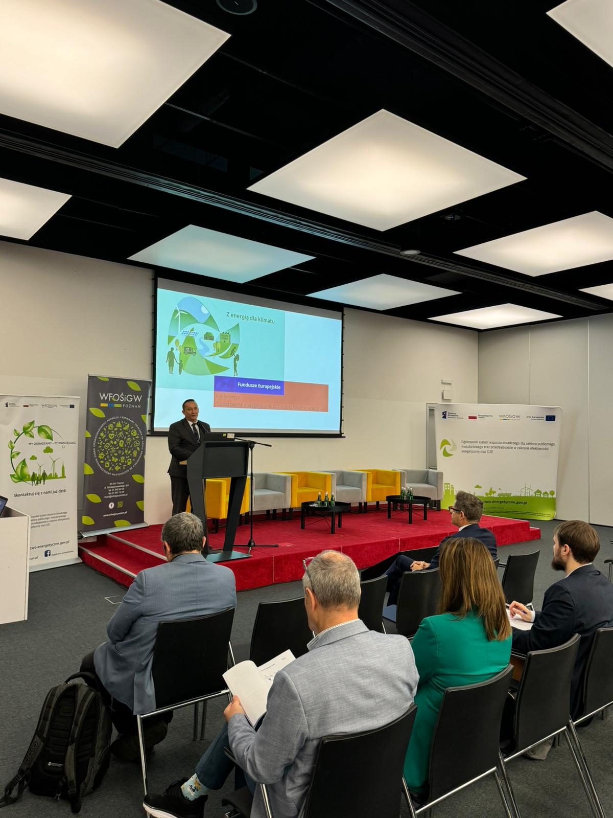 Jedna osoba stoi na scenie i wygłasza przemówienie.