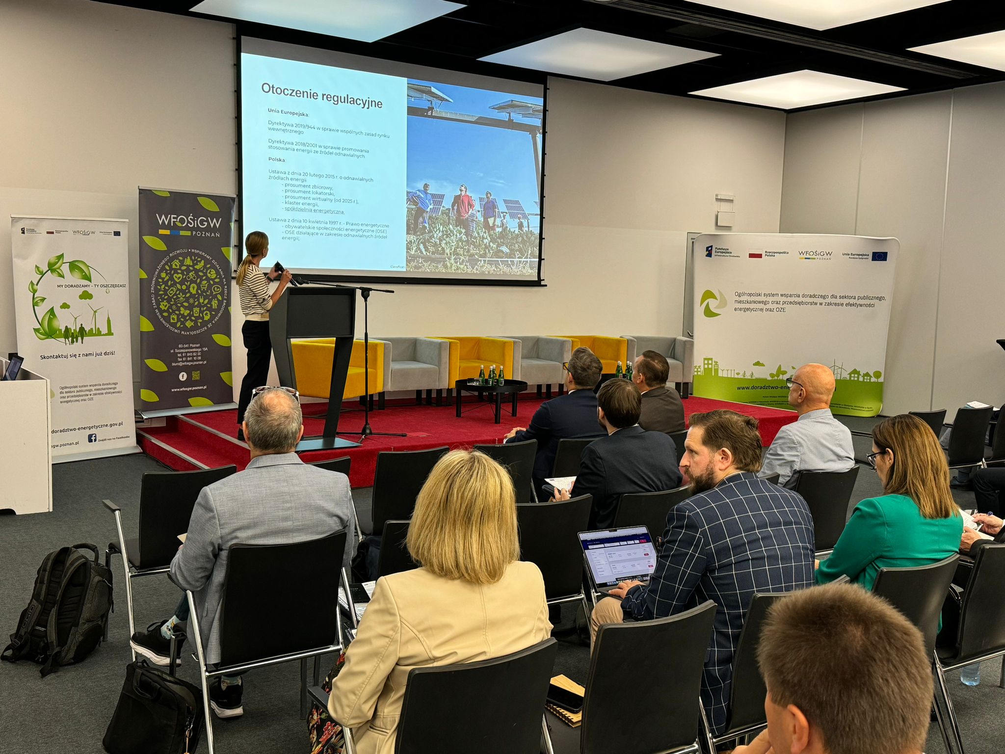 Sala wypełniona uczestnikami konferencji, a na scenie prelegent omawia prezentację.