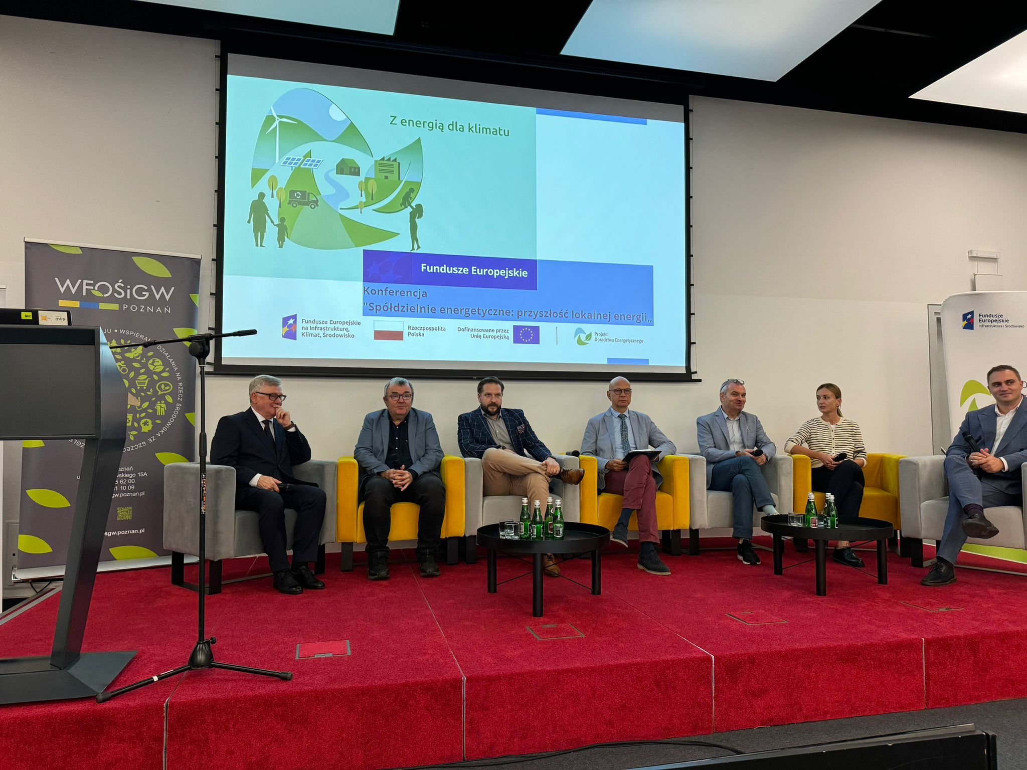 7 osób - prelegentów konferencji - siedzi na scenie na fotelach i odpowiada na pytania uczestników konferencji.