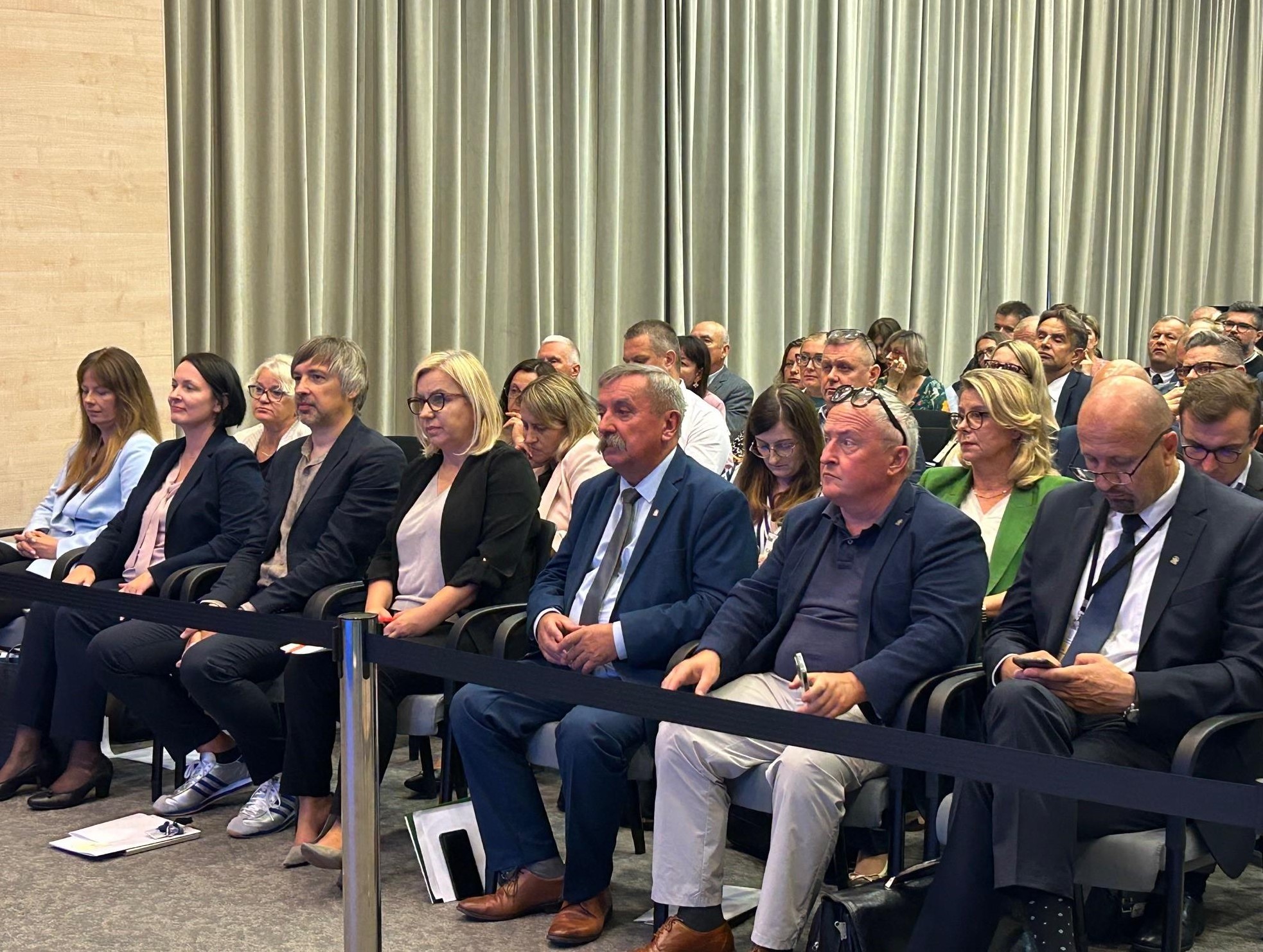 Widok na salę, na której na krzesłach siedzą uczestnicy spotkania.