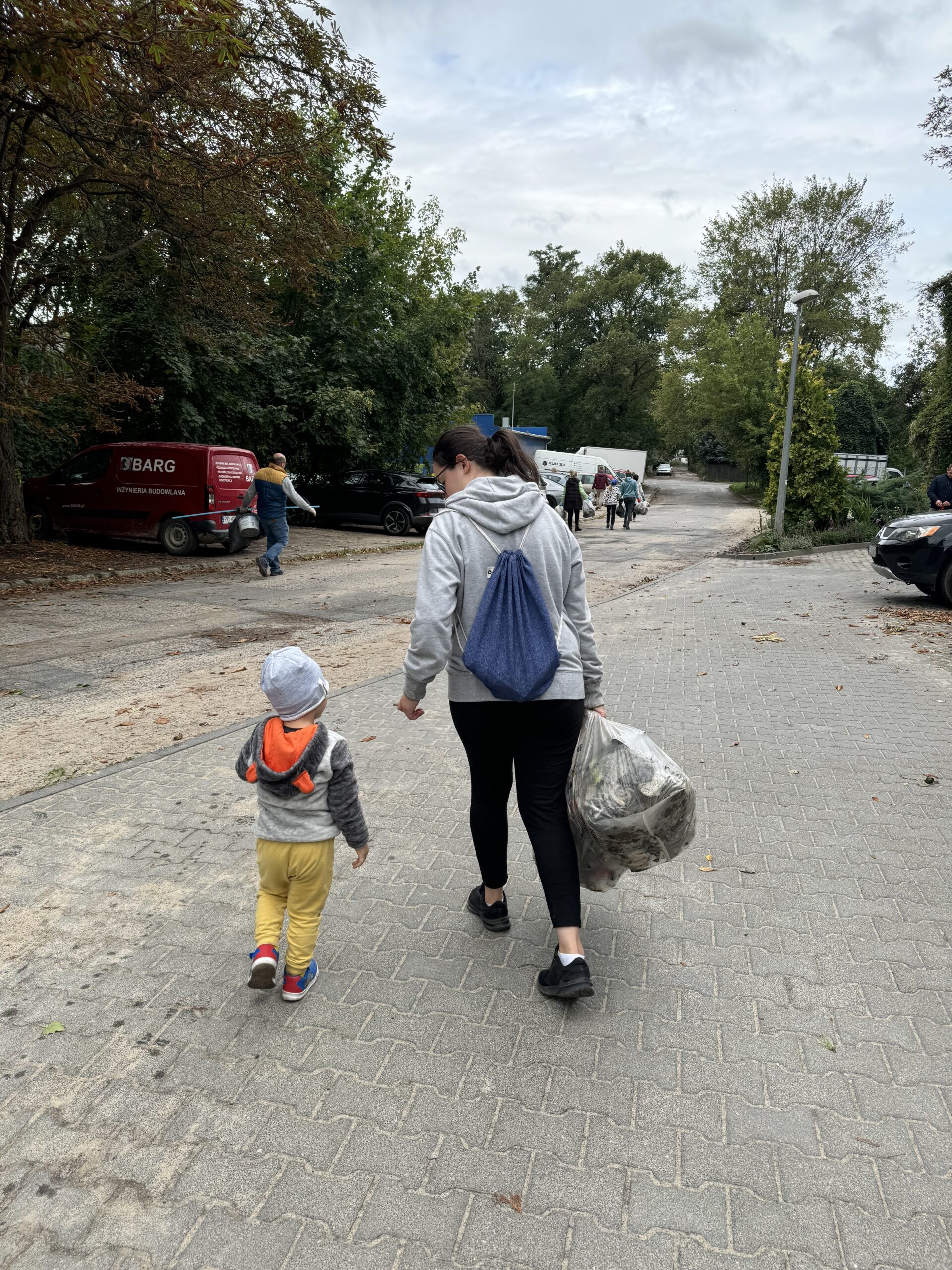 Pracownicy WFOŚiGW w Poznaniu podczas sprzątania okolicy w ramach akcji "Sprzątanie świata 2024" niosą worki nazbieranych odpadów.
