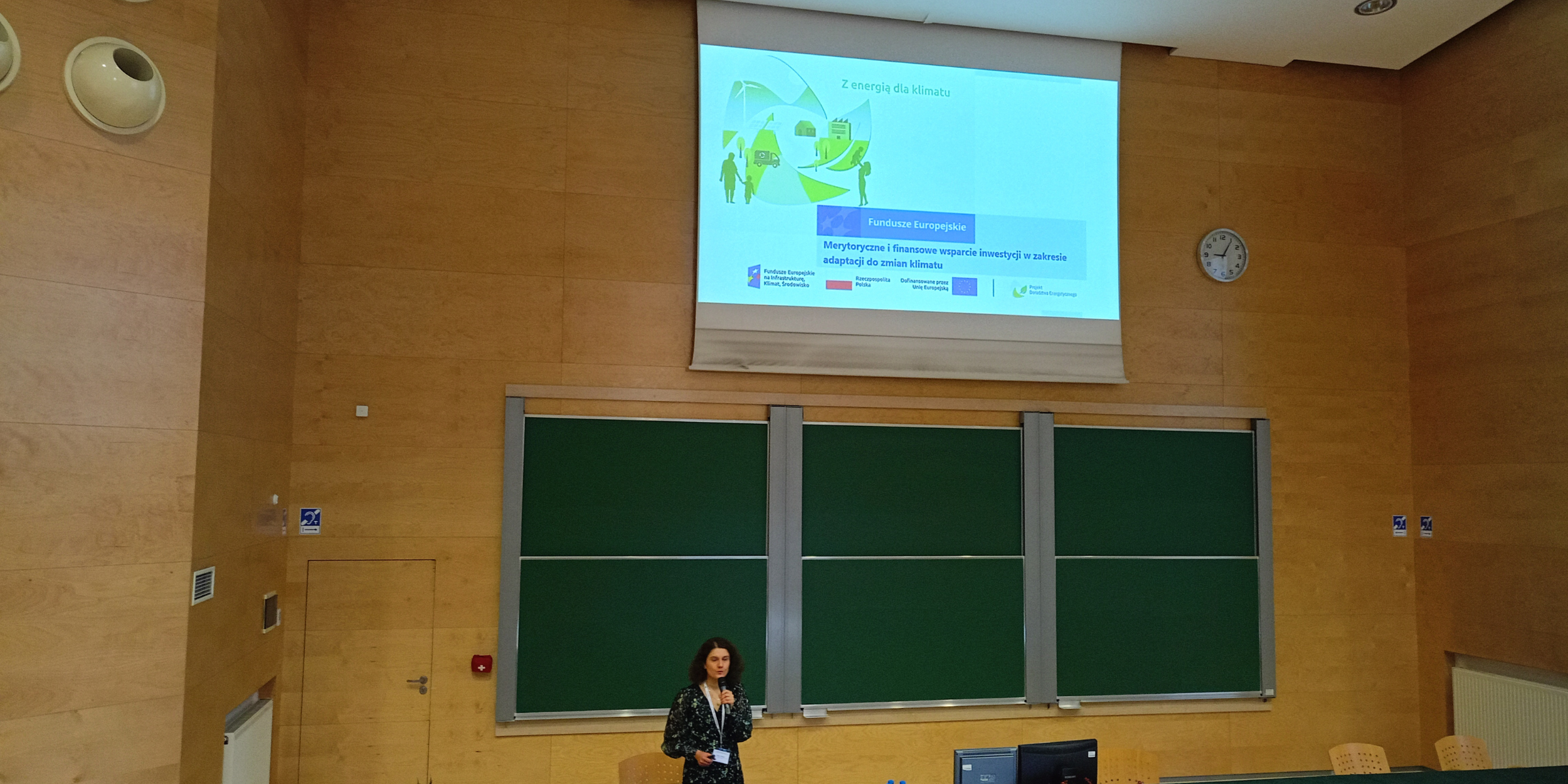 Jedna osoba stoi na scenie na środku i wygłasza prelekcję.