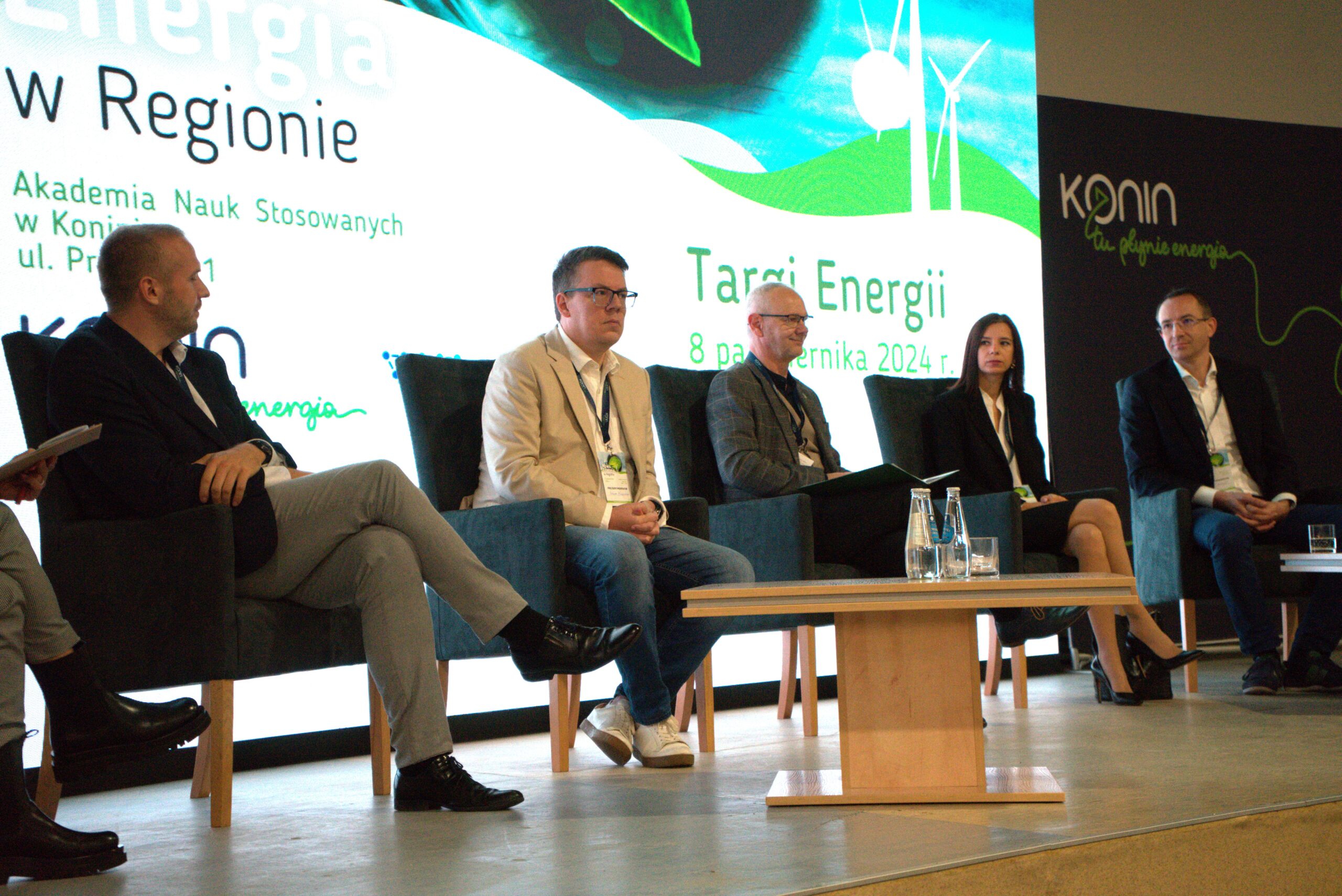 Na tle ekranu prohejktora na podeście siedzi na krzesłach 5 osób, które biorą udział w dyskusji.