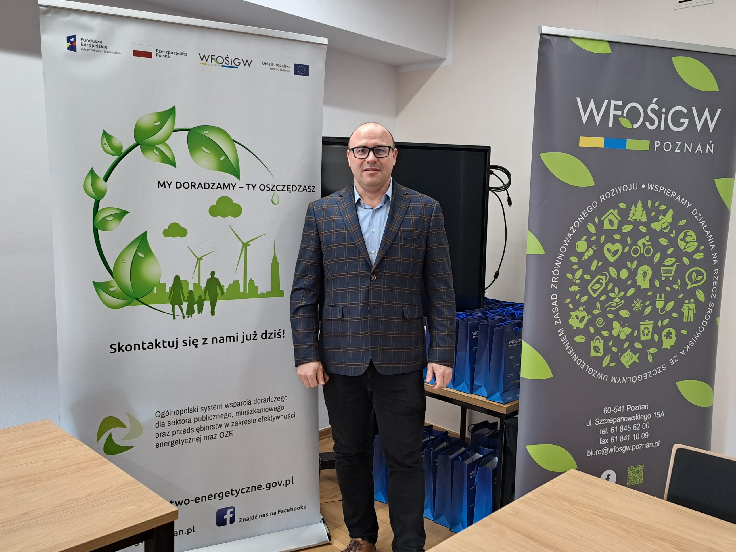 Na tle upominków i rollupów stoi jedna osoba.