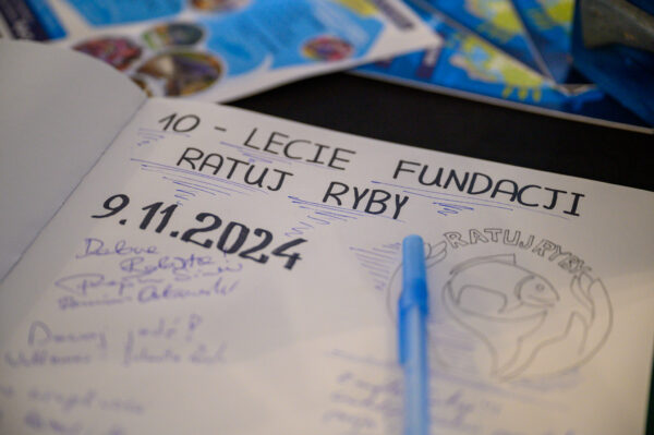 Zdjęcie przedstawia z bliska księgę gości wydarzenia, jakim jest 10-leciee Fundacji "Ratuj Ryby".