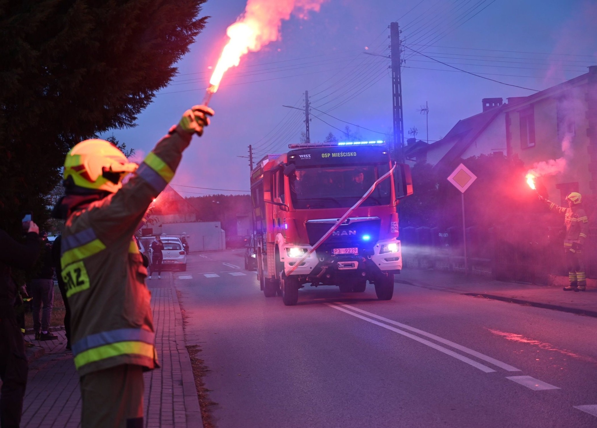Na zdjęciu przejazd nowego wozu ratowniczo-gaśniczego przy odpalonych przez strażaków flarach.
