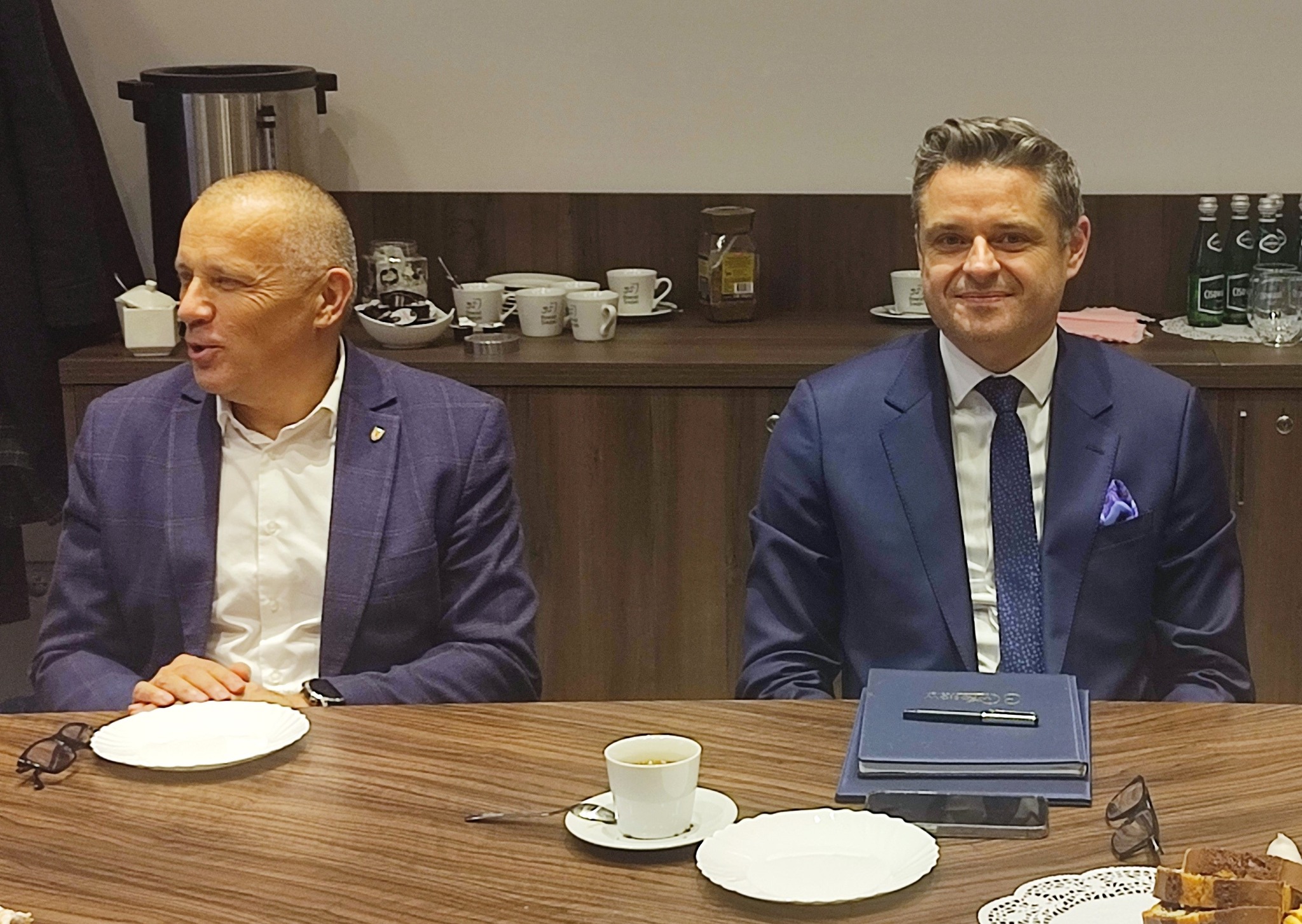 Zdjęcie przedstawia 2 osoby, które siedzą za stołem.