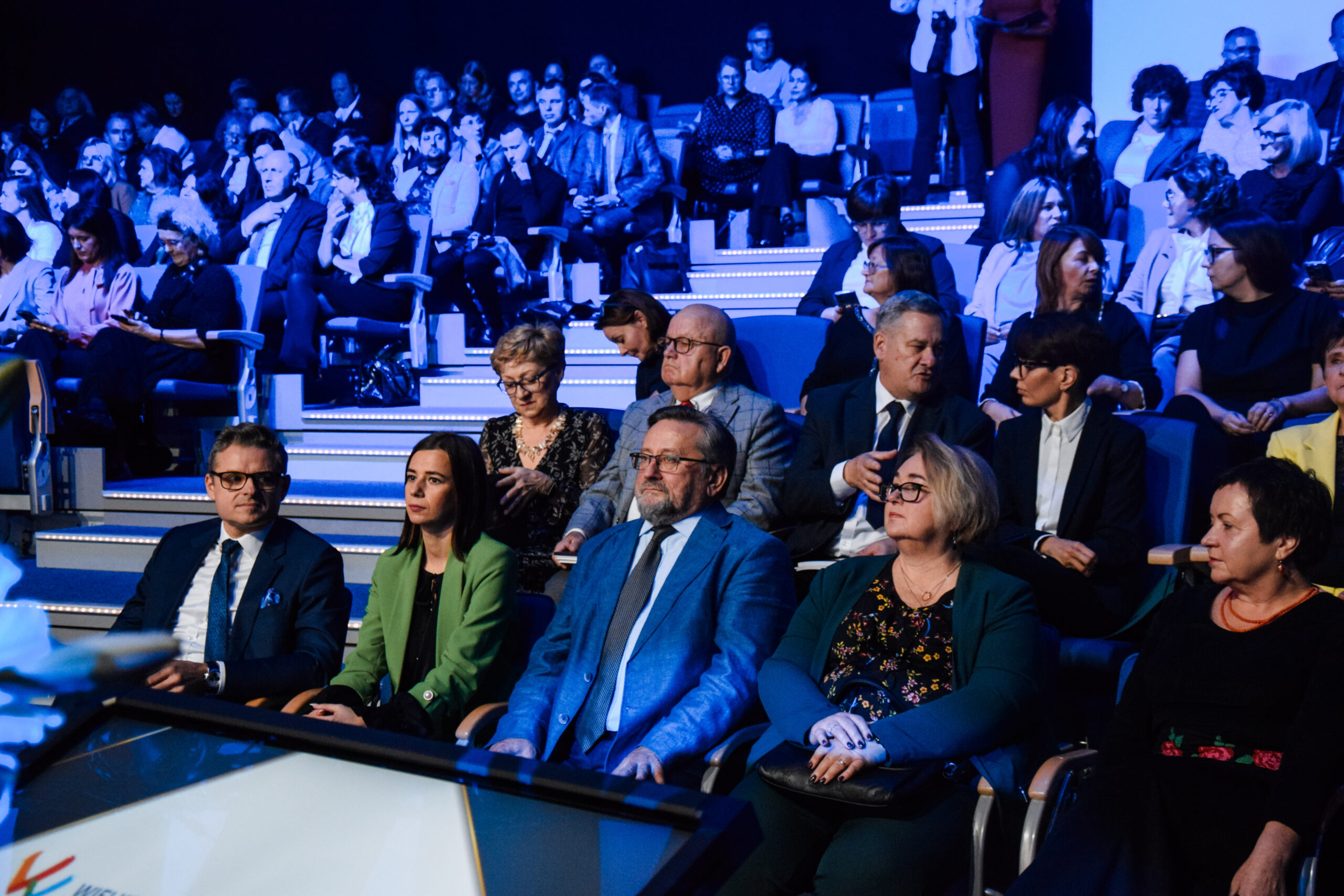 Zdjęcie przedstawia gości zaproszonych na galę, którzy siedzą na krzesłach na widowni.