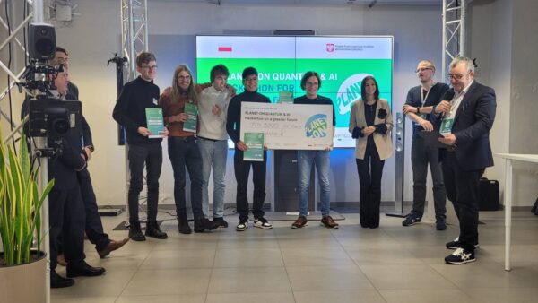 Na tle ekranu na środku sali stoi 10 osób i pozuje do zdjęcia.