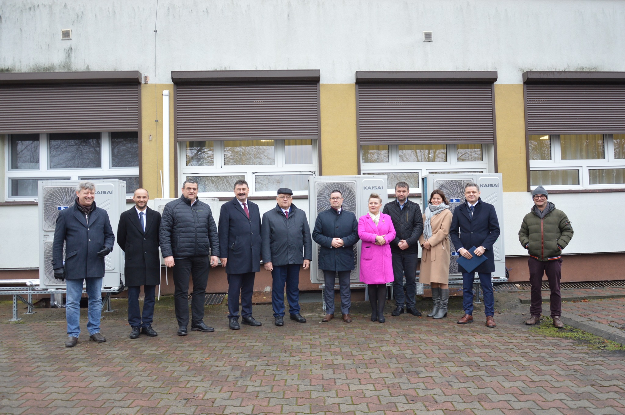 Na zdjęciu stoi 11 osób, zaproszonych gości, na tle otwieranej inwestycji.