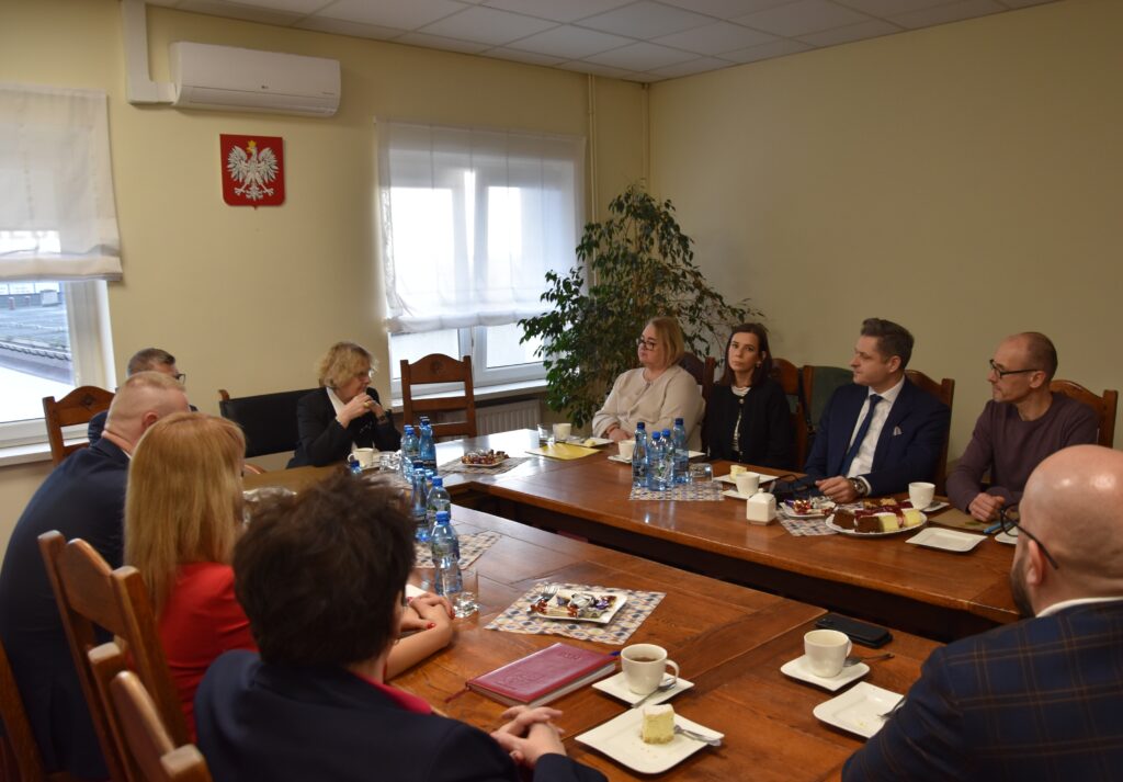 Osoby siedzą wokół stołu i rozmawiają.