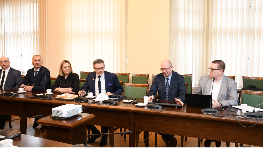 Na zdjęciu kilka osób siedzi przy stole i rozmawiają.