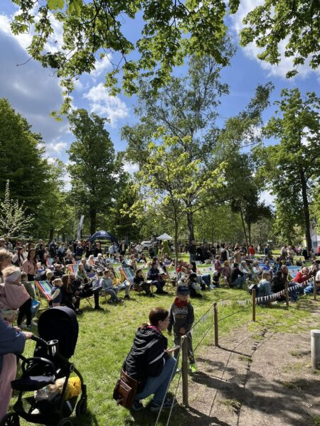 Zdjęcie przedstawia strefę relaksu podczas pikniku - leżaki rozłożone na trawie i ludzi korzystających z nich.