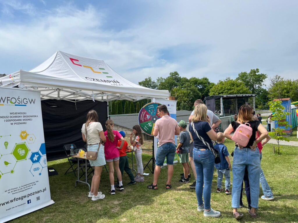 Stoisko WFOŚiGW w Poznaniu i koło fortuny, a przy nim rodziny podczas zabawy.