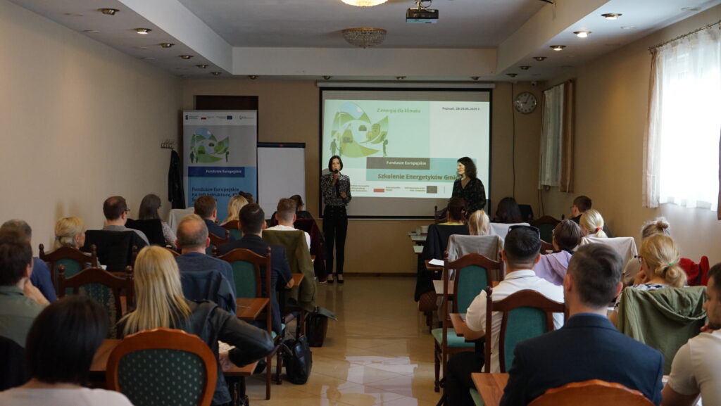 Zdjęcie przedstawia widok na salę, na której odbywa się szkolenie, na przodzie sali wyświetlona jest prezentacja, a osoby uczestniczące w szkoleniu siedzą na krzesłach.