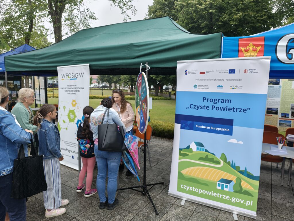 Zdjęcie przedstawia stoisko WFOŚiGW w Poznaniu, na którym widać ludzi uczestniczących w zabawie "Ekologiczne koło fortuny".