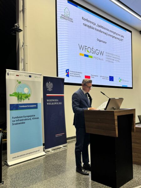 Zdjęcie przedstawia widok na salę podczas konferencji i na scenie na mównicy stoi jedna osoba i przemawia do uczestników.