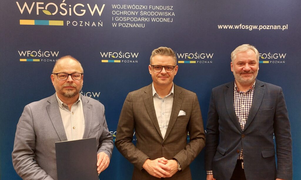 na zdjęciu 3 osoby stoją obok siebie na ściance reklamowej