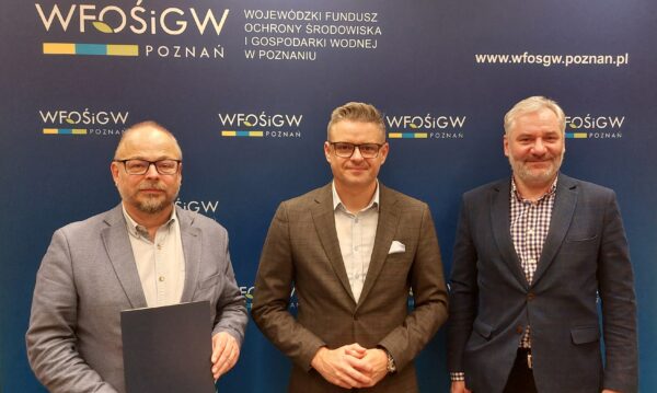 na zdjęciu 3 osoby stoją obok siebie na ściance reklamowej